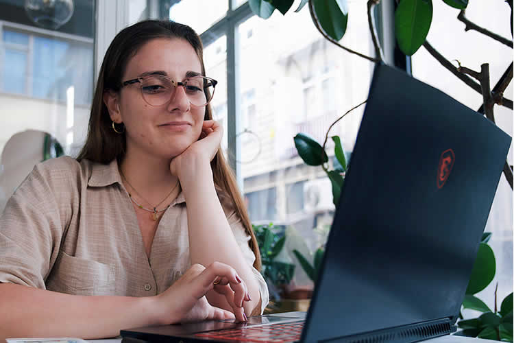 A young professional woman working on a laptop in a café.